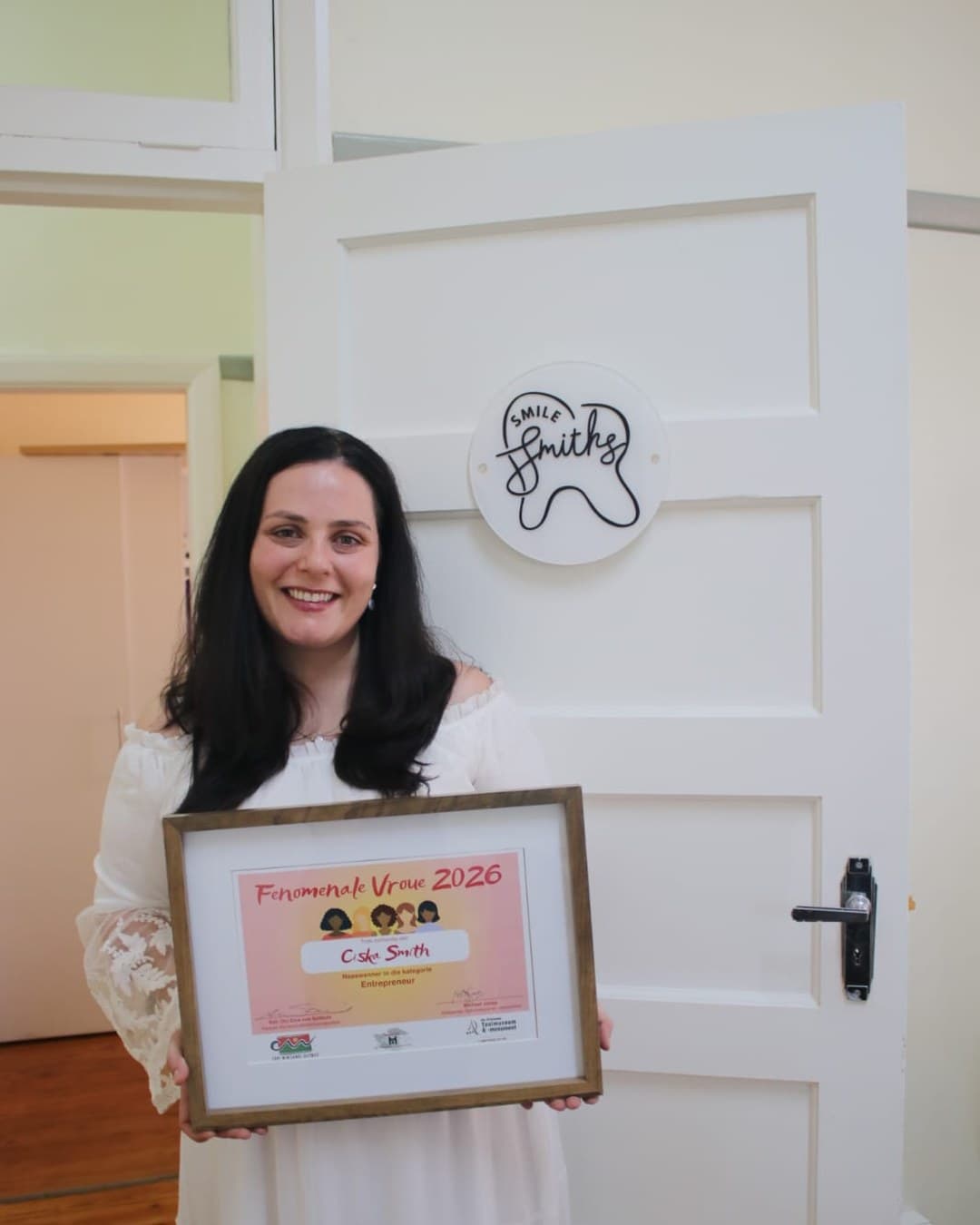 Ciska at the SmileSmiths practice, holding her Fenomenale Vroue 2026 certificate